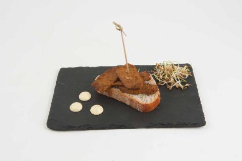 Cerdo cortado a tiras, adobado con especies sobre una rebanada de pan bañada con maionesa al curri