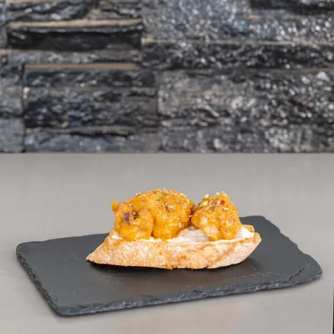 Tostada crujiente de cazón rebozado y frito con pimiento verde asado, aliñado con un toque de ajo y aceite de oliva