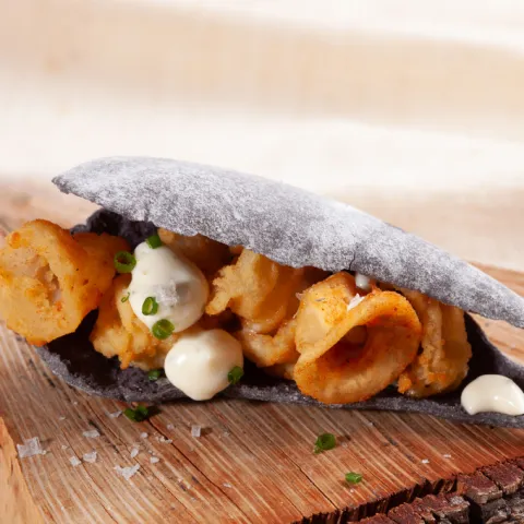 Pan artesano con forma y textura de caparazón de mejillón, relleno de calamares a la andaluza y acompañados de una fresca mayonesa de menta.