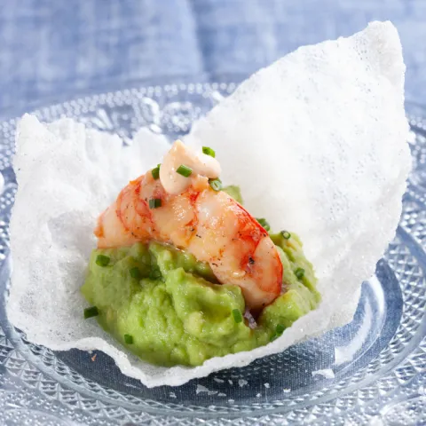 Gamba a la plancha sobre una base de pan de arroz frito y una palta de aguacate, con un toque de mayonesa de kimchi.