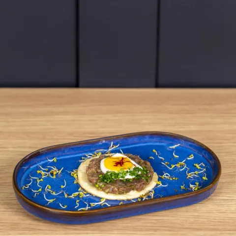 Steak tartar de carne madurada sobre oblea frita y acompañado con huevo de codorniz