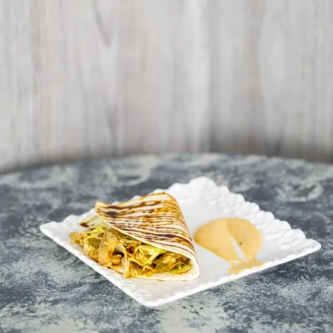 Tortilla de maíz rellena de pollo con verduras, queso rallado, miel de caña y salsa chipotle