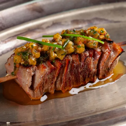 Brocheta de Wagyu y torreznos de Soria a la brasa con chimichurri de mango.
