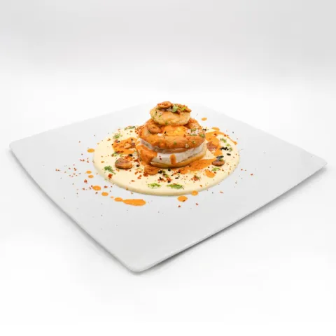 Salaílla artesana rellena de brandada de bacalao con huevo de gallinas felices, ali oli de patata, salsa de piquillos, chip de ajo y tierra de jamón