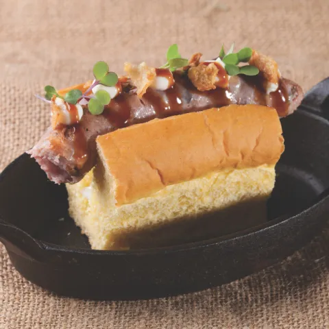 Brioche de mantequilla con salchicha del Picapedrer delgada rellena de setas de temporada, salsa teriyaki y cebolla crujiente caramelizada