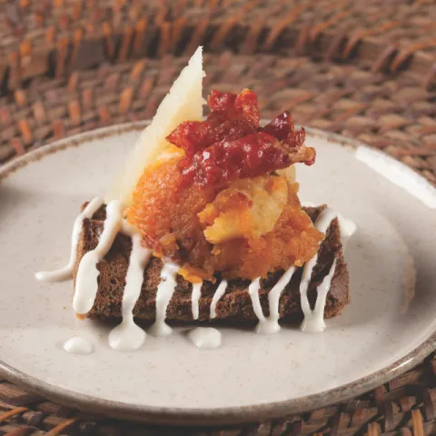 Tostada de cerales con sofrito de calabaza y membrillo con crema de queso manchego y crujiente de ibérico.