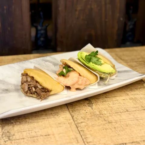 Tres panes caseros de maíz con distintos rellenos: emulsión de pollo confitado, langostino en salsa rosa y ternera con queso fundente