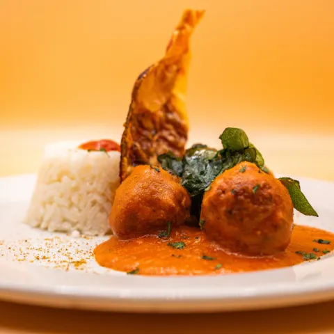 Albóndigas elaboradas siguiendo métodos tradicionales con mezcla de carnes para lograr textura y sabor complejos. Salsa de cebolla y especies africanas.