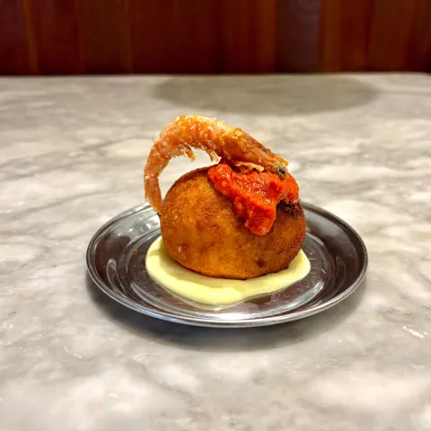 Bomba de la Barceloneta marinera con relleno de pescado de roca y gambas, alioli cítrico y brava ahumada. Precio: 5,00 €