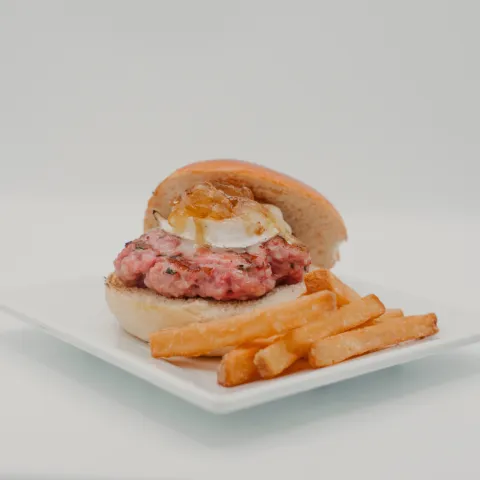 Zona B. Un clásico reinventado para sorprender. El pan brioche envuelve una jugosa cheeseburger, el carácter del rulo de cabra y el toque dulce de la cebolla caramelizada, dando vida a una tapa que se disfruta al ritmo del mejor verano.