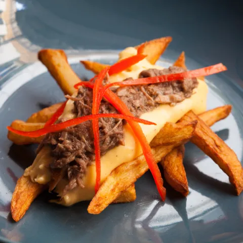 Estofado de rabo de toro cocinado a baja temperatura sobre una cuna de patatas fritas naturales y salsa de queso