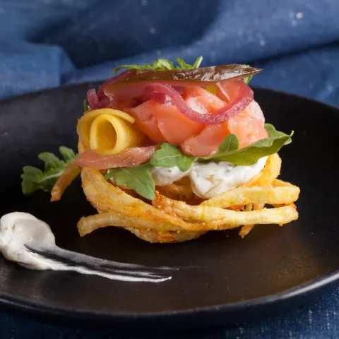 Niu de patata ratllada lleugerament fermentada amb salmó fumat casolà i formatge cremós casolà, o versió vegetariana amb bolets fregits i cogombrets fermentats.