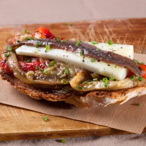 Tostada de escalivada con una anchoa de L’Escala y queso de cabra.