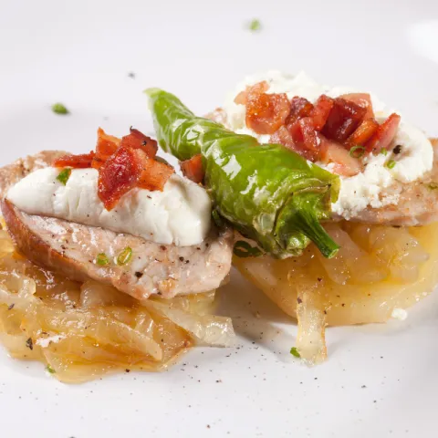 Base de patata amb ceba caramel·litzada, filet ibèric, formatge de cabra i bacó cruixent