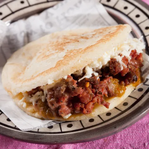 Arepa de sabroso chorizo criollo, salsa chimichurri y queso.