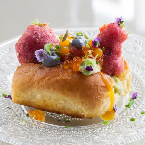 Minibrioche de mantequilla y sal ahumada con tempura roja de gamba, vinagreta de fruta de la pasión, mayonesa de ajo negro y sweet chilli con lima , huevos de trucha, caviar de mango y brotes tiernos