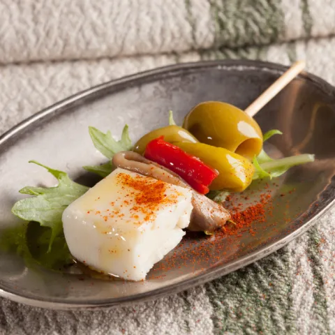 Formatge curat, anxova, pebrot, bitxo i oliva, amanits amb un toc d'oli d'oliva verge extra.