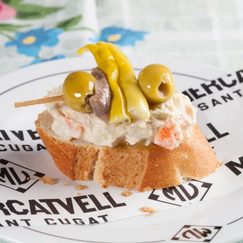 Barqueta d'amanida russa amb gilda d'anxova, bitxo i olives.