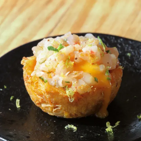 Patacón de plátano en forma de canasta rellena de crema de setas, fuagràs, yema de huevo cocinada a baja temperatura y tartar de gamba con salsa de marisco