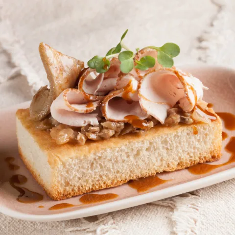 Focaccia crujiente con carne ibérica asada a baja temperatura, duxelle de setas de temporada y cebolla confitada. Terminada con una cremosa salsa elaborada con nata culinaria y la reducción de los jugos del asado.
