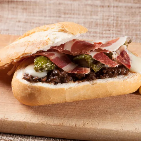 Queso Torta del Casar sobre una base de morcilla con pimientos de Padrón y jamón ibérico.