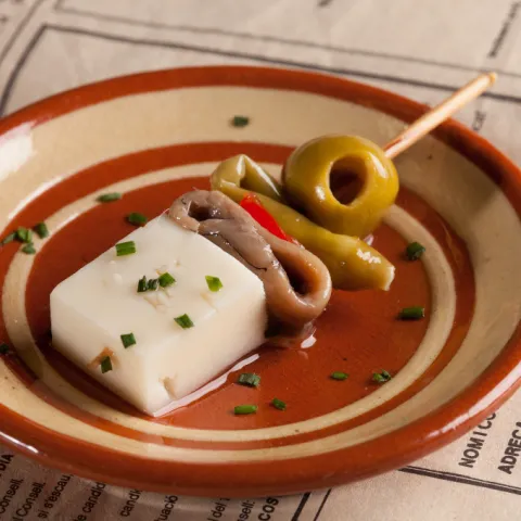 Formatge curat, anxova, pebrot, bitxo i oliva, amanits amb un toc d'oli d'oliva verge extra.