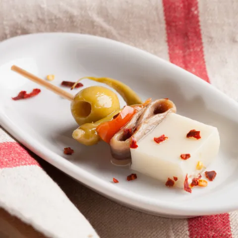Formatge curat, anxova, pebrot, bitxo i oliva, amanits amb un toc d'oli d'oliva verge extra.