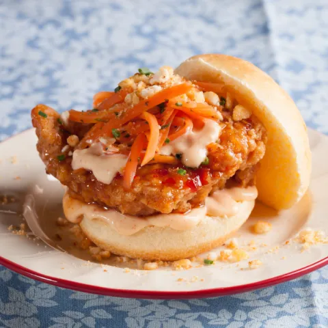 Mini entrepà de pollastre coreà amb salsa sweet chili, cogombre sunomono, pastanaga envinagrada, maionesa de kimchi i pols de blat de moro torrat.