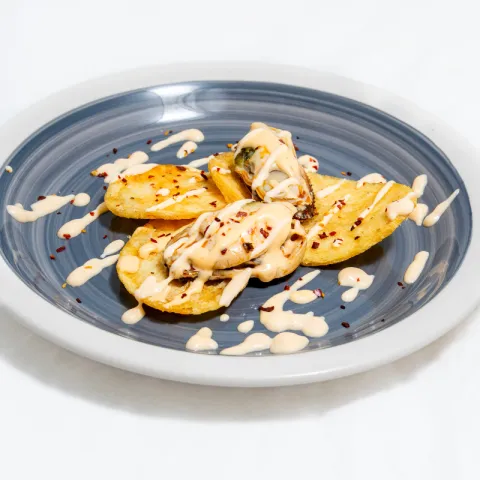 Patatas, acompañadas de mejillones y de una salsa de mayonesa, escabeche y un toque picante
