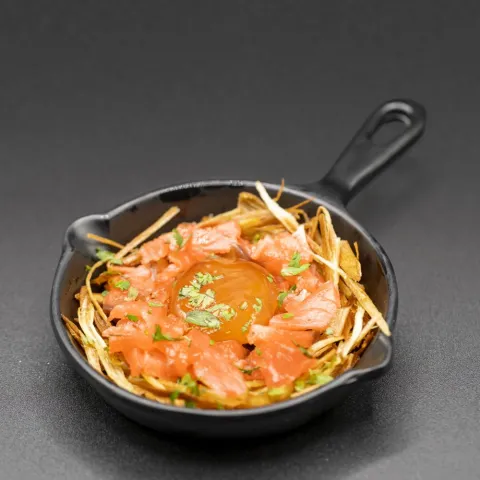 Salmón marinado sobre una cama de puerro frito coronado con una yema de huevo marinada