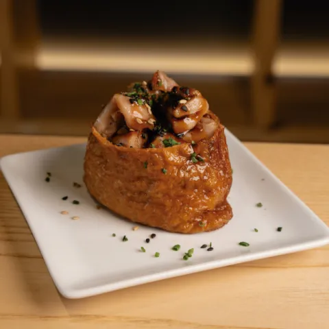 Arroz Royal Umbrella mezclado con arroz La Fallera, tofu inari, contramuslo de pollo marinado, salsa teriyaki, cebollino y sésamo por encima