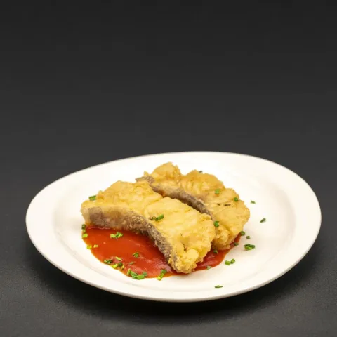 Bacalao rebozado y frito sobre una cama de salsa de tomate casera