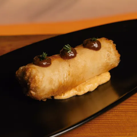 Rollito crujiente relleno de carrillera con puré de boniato y salsa de vino tinto