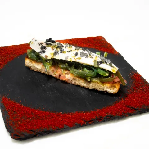 Tomate, boquerón y alga wakame sobre pan de cristal