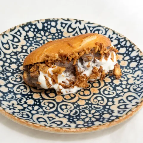 Brioche de carrillera al vino tinto y miel, con crema suave de queso y cebolla crujiente