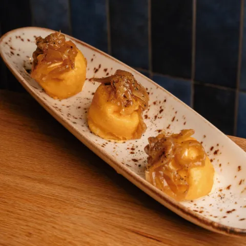 Esfera frita de parmesano con crema de queso de cabra, sobrasada y cebolla caramelizada