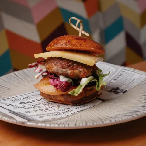 Minihamburguesa de vedella i sobrassada, formatge Maó, panet de pa de coca, patata i pebre vermell de tap de cortí