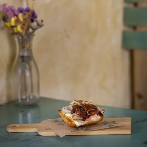 Una tosta de pan cristal con solomillo de cerdo y queso brie fundido acompañado con cebolla caramelizada
