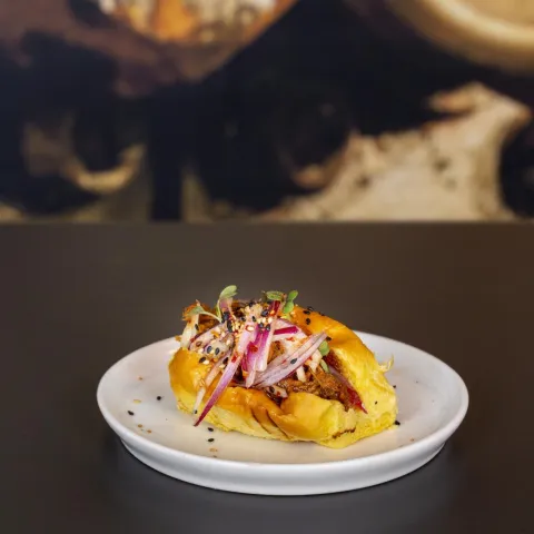 Brioche relleno de pulled pork meloso con salsa hoisin y cebolla encurtida agridulce
