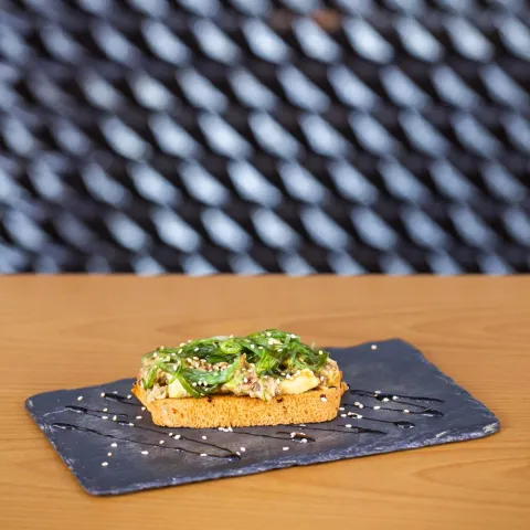 Tosta de pan brioche con atún, aguacate, alga wakame aliñada con aceite de oliva y soja, con decoración de Pedro Ximénez y semillas de sésamo