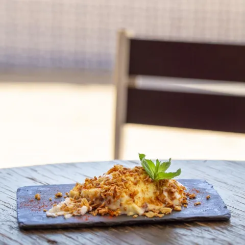 Bacalao con un gratinado de muselina de mango y cebolla frita con base de ajoblanco