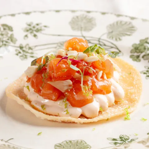 Oblea crujiente con tartar de salmón, mayonesa de limón, Sriracha y crujiente de avellana tostada.