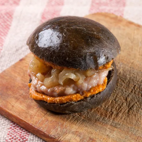 Pan de brioche negro elaborado con cerveza Bock Damm y hamburguesa de pollo con avellanas DOP Reus y AOVE DOP Siurana.