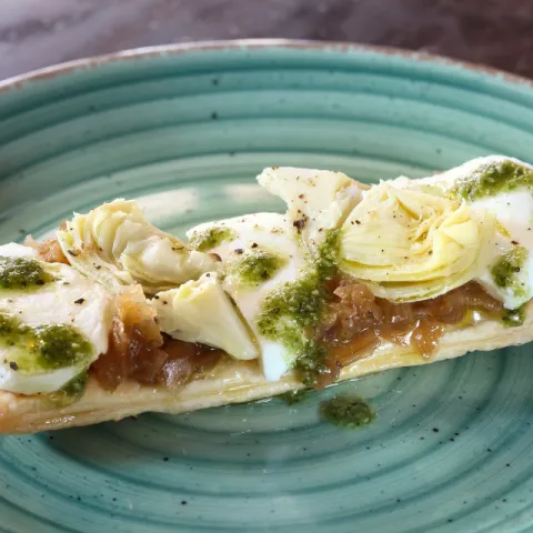 Coca con alcachofa, cebolla confitada, mozzarella y pesto