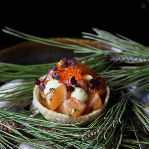 Dados de salmón fresco en una delicada cestita crujiente, acompañados de una suave emulsión de wasabi y lima, aguacate y brotes tiernos 