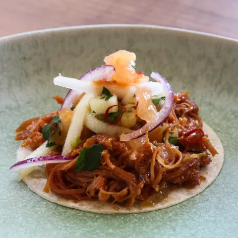 Taco de trigo con pulled pork, cebolla caramelizada, pico de gallo y mermelada de jengibre