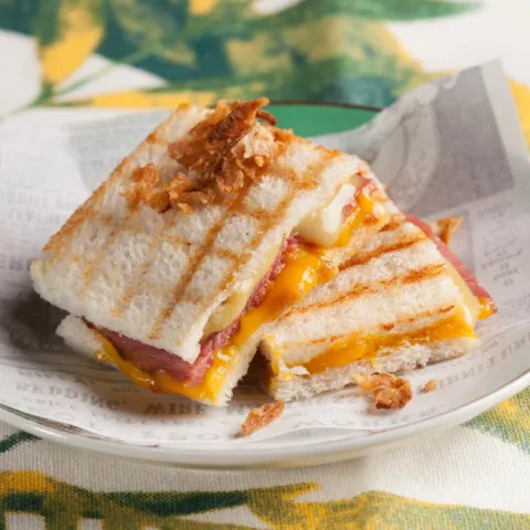 Bikini amb pa per tramezzini, mantega fosa, pastrami italià amb formatge cheddar fos, ceba crixent i un punt de mostassa a la mel.