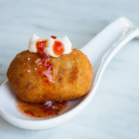 Croqueta de gamba sobre un lecho de salsa agridulce y picante con un toque de nuestra salsa M’Encanta