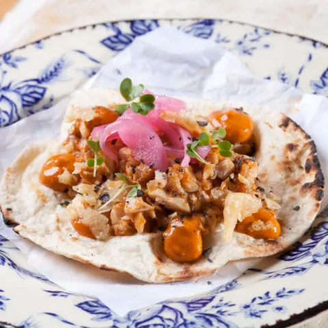 Pollo asado con su jugo, cebolla de Figueres confitada en vinagre, romesco y crujiente de parmesano.