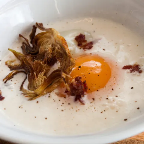 Huevo cocinado a 63 ºC,  espuma de parmesano con polvo de jamón y chips de alcachofa